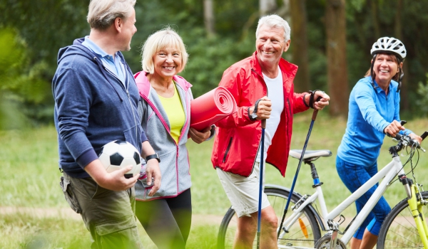 Four smiling adults head out to do exercise outdoors.
